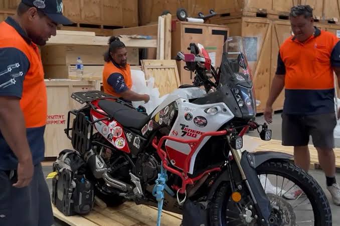 Adventure motorcycle secured to a wooden pallet in a warehouse before shipping to Florida