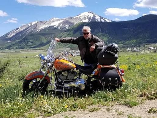 Rider beside a touring motorcycle after it arrived for a winter of riding