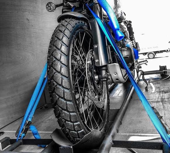 Motorcycle wheel locked in a wheel chock with blue soft tie-down straps before a Florida delivery