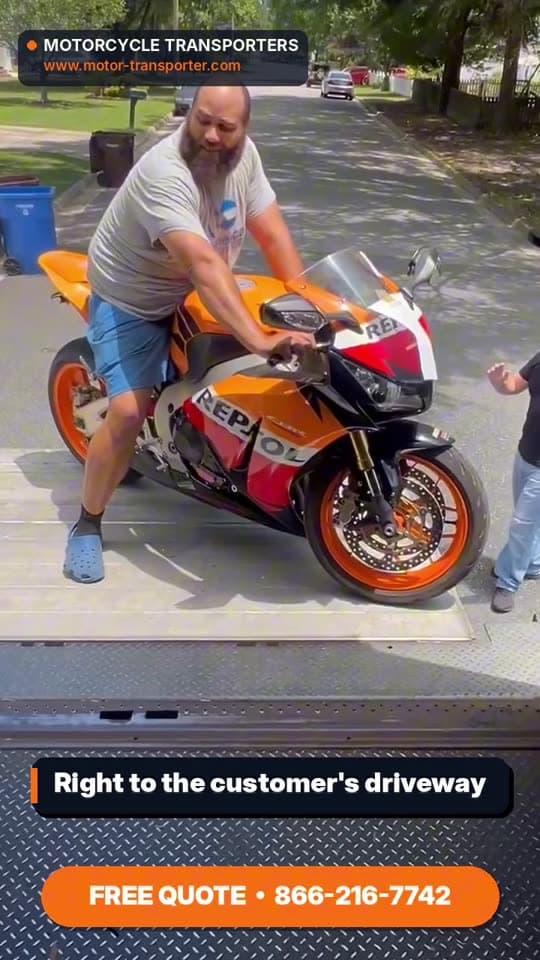 Motorcycle Transporters driver rolling a sport bike off the liftgate of a large enclosed truck in a customer driveway